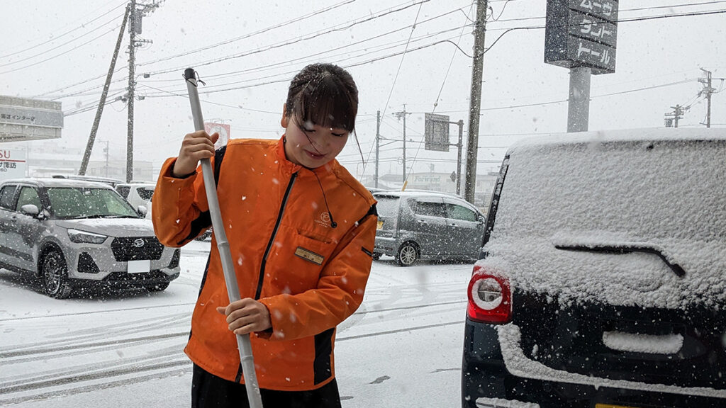 雪の中掃除する女性スタッフ